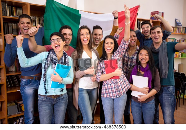 Smiling students with raised hands presenting Italy with\
flag 