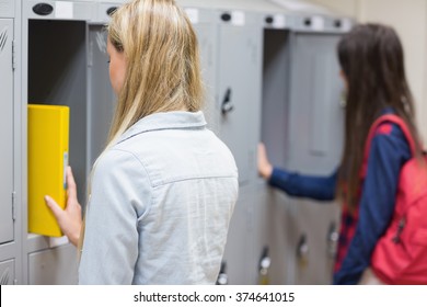 Smiling students using locker at university - Powered by Shutterstock