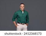 Smiling stylish middle aged business man, happy older mature businessman professional executive wearing green shirt looking at camera standing isolated on gray background. Portrait. Copy space.