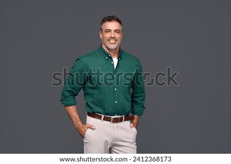Smiling stylish middle aged business man, happy older mature businessman professional executive wearing green shirt looking at camera standing isolated on gray background. Portrait. Copy space.
