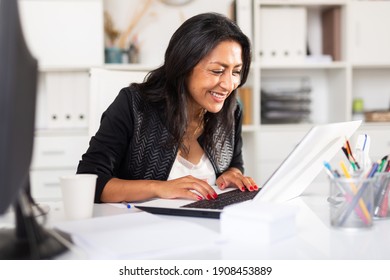 Smiling Successful Hispanic Business Woman Working On Laptop In Modern Office