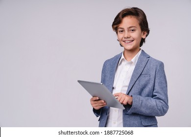 Smiling successful young boy in formal attire writting on clipboard isolated over grey background - Powered by Shutterstock