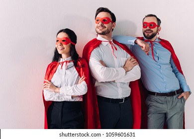 smiling super businesspeople in masks and capes looking away isolated on white - Powered by Shutterstock