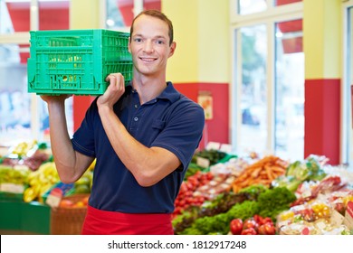 Smiling supermarket employee carries a box of fruit - Powered by Shutterstock