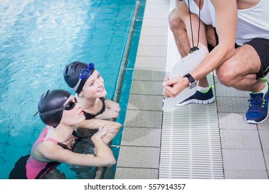 Smiling swimmers looking at clipboard at leisure center - Powered by Shutterstock