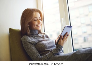 Smiling talented beautiful female student of university messaging with classmates using connection to internet via modern smartphone and texting funny feedback to followers in social networks