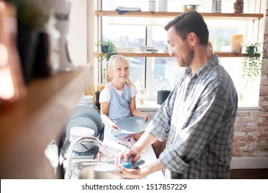 Smiling and talking. Lovely beautiful daughter smiling and talking to daddy washing the dishes - Powered by Shutterstock