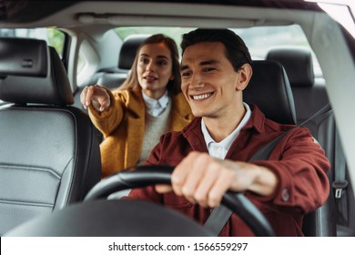 Smiling Taxi Driver With Woman Passenger Pointing On Road 