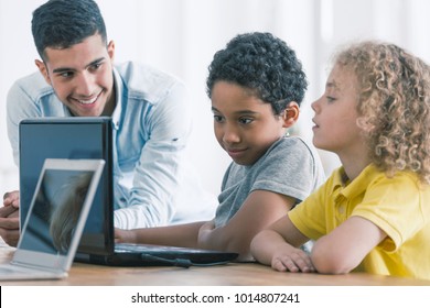 Smiling teacher and afro-american boy playing video game in the school - Powered by Shutterstock