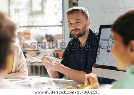 Smiling teacher explaining group pf kids how quadcopter works