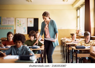 Smiling teacher helping schoolboy with his assignment on a class at elementary school. - Shutterstock ID 2183353387