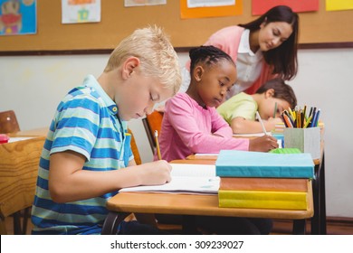 Smiling Teacher Helping A Student At The Elementary School