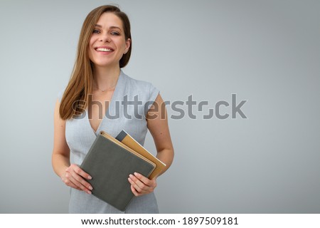 Smiling teacher holding books and standing near to copy space. Isolated female portrait.