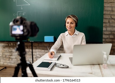 Smiling Teacher Holding Online Lecture From The Classroom During COVID-19 Lockdown.