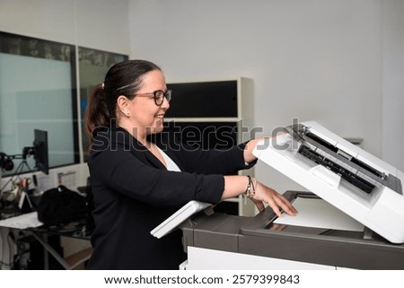 Smiling teacher preparing documents for her students, using a photocopier in a language academy