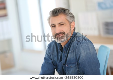 Smiling teacher sitting at desk in university office