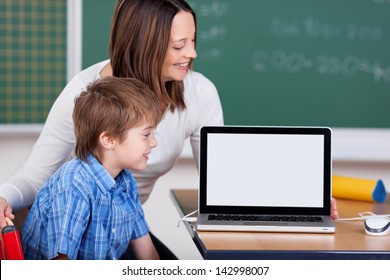 Smiling teacher and student learning from laptop in the classroom