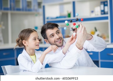 Smiling teacher and student scientists looking at molecule model in lab - Powered by Shutterstock