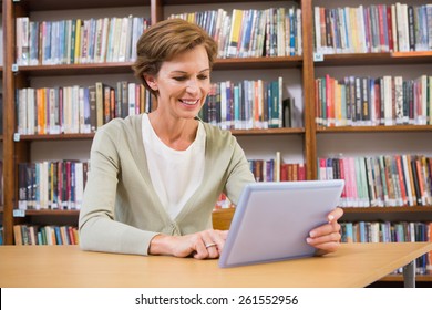 Smiling teacher using tablet pc at library at elementary school