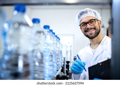 Smiling technologist working in bottling factory controlling production of drinking water and PET packaging. - Powered by Shutterstock