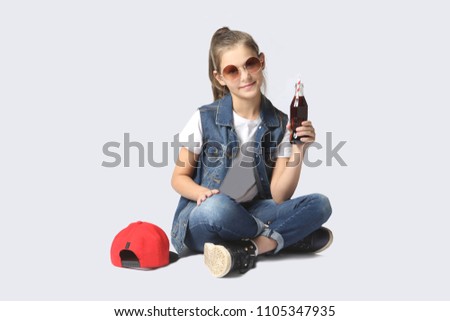 smiling teen girl in casual clothes and sun glasses on a gray background. Teen's fashion. 