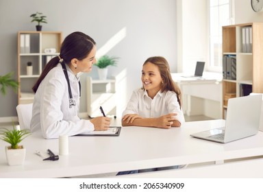 Smiling Teen Girl Child Speak Talk With Female Doctor At Consultation In Clinic. Caring Woman Pediatrician Checkup Consult Happy Little Kid Patient In Hospital. Good Medical Service, Healthcare.