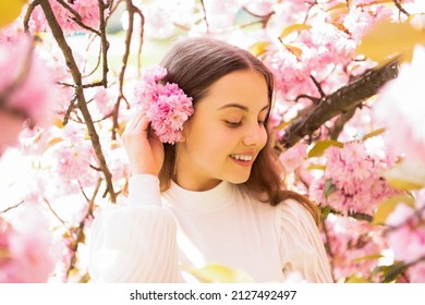 smiling teen girl at sakura flower bloom in spring