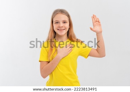 Smiling teen girl wearing casual yellow t shirt, swearing with hand on chest and open palm, making a loyalty promise oath, promising to be honest, telling truth. White background
