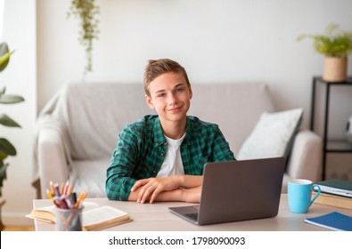 Smiling Teen Guy Studying At Home, Using Laptop, Making Homework