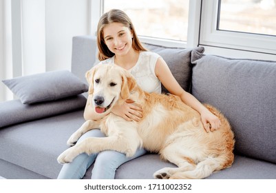 Smiling teenage girl with adorable dog in light room - Powered by Shutterstock