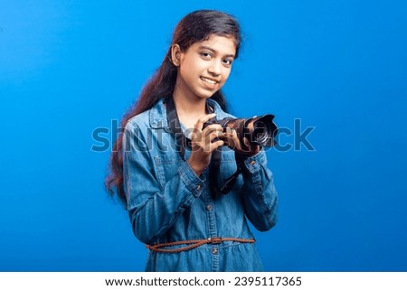 Smiling teenage girl clutching DSLR camera