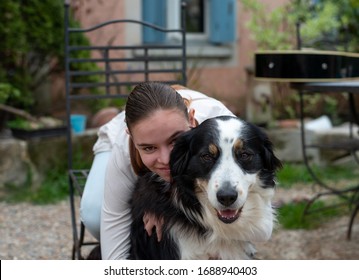 Smiling Teenage Girl Hugging  Large Dog In Garden. Love Of Animals.