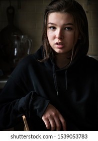 Smiling Teenage Girl In A Jacket With A Hood At Home In A Dark Room, Real People Every Day Life