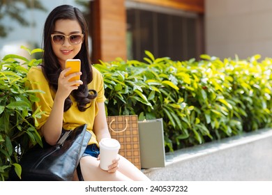 Smiling teenage girl with phone texting outdoors - Shutterstock ID 240537232