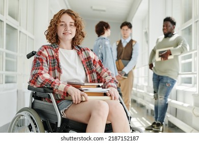 Smiling teenage girl with physical disability in casualwear sitting in wheelchair in college corridor against group of classmates - Powered by Shutterstock