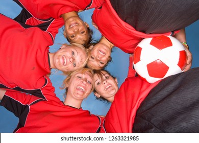 Smiling Teenage Girls In Soccer Team Uniforms In Huddle At Camera