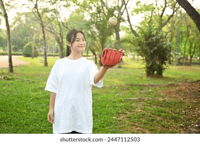 Smiling teenaged girl playing baseball in the park on a sunny spring day - Powered by Shutterstock