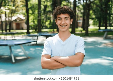 Smiling teenager boy with braces holding hands folded looking at camera at the park. Lifestyle emotions concept - Powered by Shutterstock