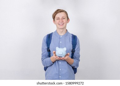 Smiling Teenager Boy Holding Piggy Bank Over White Background. Financial Education Savings Concept.