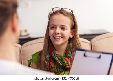 Smiling teenager girl answering a professional counseling woman questions for an assessment or survey - close up