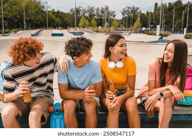 Smiling teenagers high school pupils friends classmates college students boys girls sitting on ramp skating in skate park drinking soft dings lemonade having fun laughing hanging out outside - Powered by Shutterstock