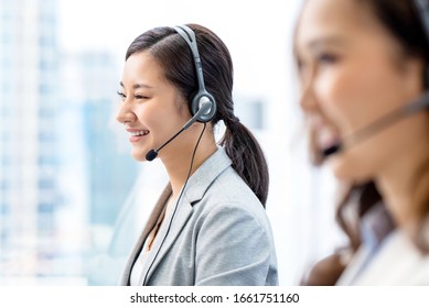 Smiling Telemarketing Asian Woman Working In Call Center Office