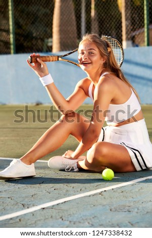 Smiling tennis girl taking a break on court