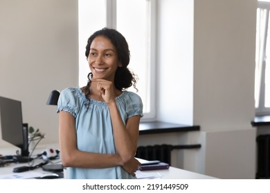 Smiling thoughtful African businesswoman pose indoor, staring into distance, thinking over project looks deep in thoughts, smile enjoy career and workday in modern office. Career, aspirations - Shutterstock ID 2191449509
