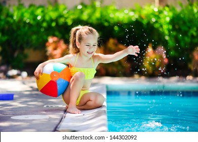 Smiling toddler girl playing with toy in outdoor swimming pool