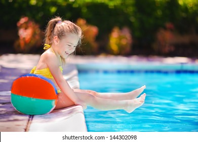 Smiling toddler girl playing with toy in outdoor swimming pool