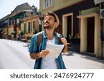 Smiling tourist sing map while walking in the city. Copy space.