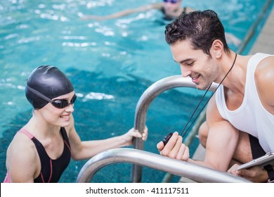 Smiling trainer showing stopwatch at swimmer at the leisure center - Powered by Shutterstock