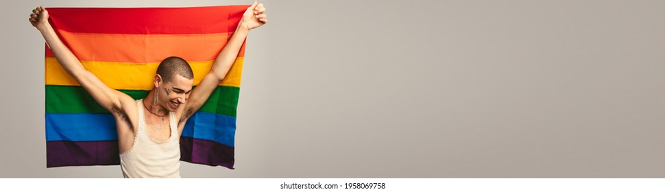 Smiling transgender man with pride flag. Cheerful man holding a lgbt flag against white background with lots of copy space. - Powered by Shutterstock