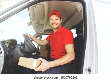 Smiling Transportation Service Driver In Red Uniform Sitting In Van With Box In Hand